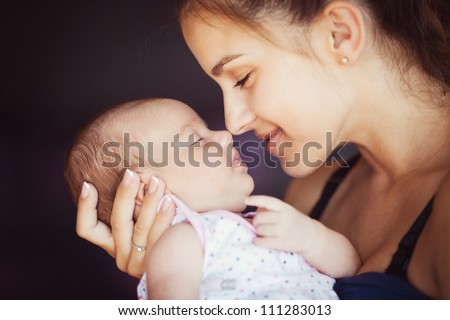 Portrait of happy young attractive mother lying with her baby on the bed at home