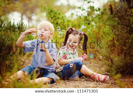 Two children in the park blowing soap bubbles and having fun