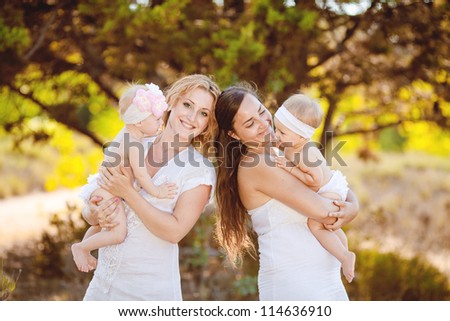 Two mothers with their children outdoor in summer park
