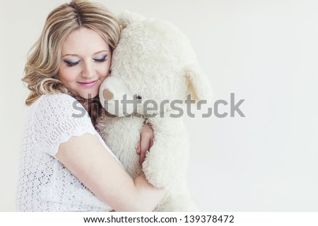 Pregnant pretty woman with toy bear. Indoor portrait