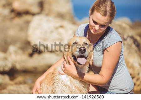 Beautiful woman with her dog playing on the sea shore. Outdoor portrait