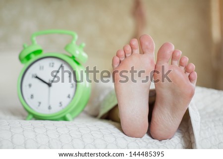Woman legs on the bed with white bed clothes