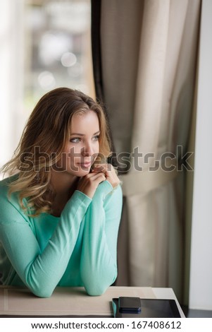 Portrait of a cute blonde smiling woman sitting in a cafe and waiting for someone
