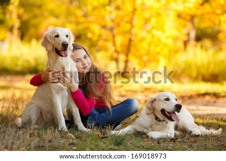 Portrait Of Beautiful Young Girl With Her Dogs Labrador Retrievers Outdoor In Autumn Beautiful Park