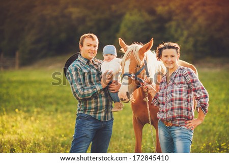 Happy Family Having Fun With Horses Outdoors On Green Field On Summer Day