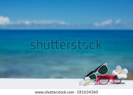 Two pair of sun glasses on a beach table on blue ocean background