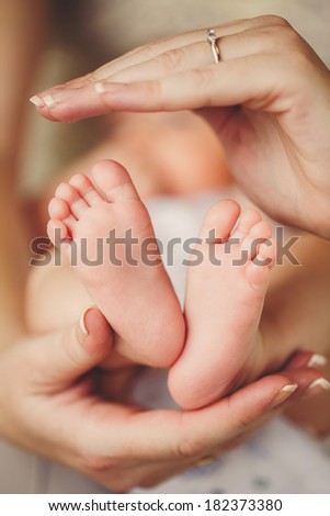 Newborn baby feet in mother hands.Masseur massaging little baby\'s foot, shallow focus