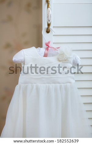 christening baby\'s dress hanging on a hanger