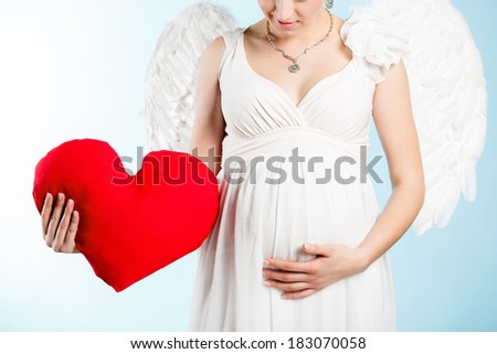 Portrait of a beautiful angelic pregnant woman. Angel with red heart in her hands