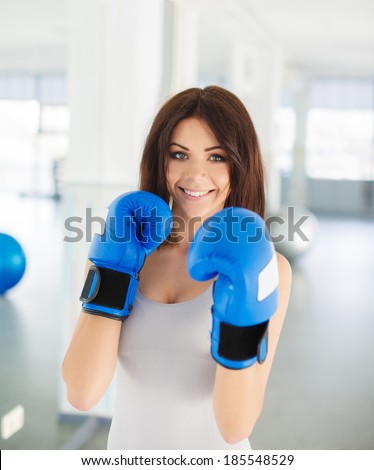 Boxer - fitness woman boxing wearing boxing gloves. Fitness boxing instructor punching fun and fresh towards camera. Beautiful mixed race Asian / Caucasian fitness girl in gym