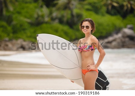 Beautiful Young Woman Surfer Girl in Bikini with Surfboard at a tropical Beach