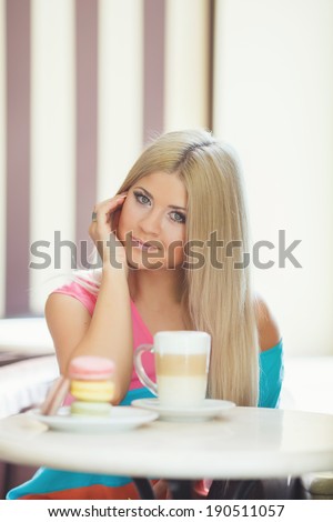 Cafe city lifestyle woman drinking coffee sitting indoor in trendy urban cafe. Cool young modern Caucasian blonde female model in her 20s. Portrait close up