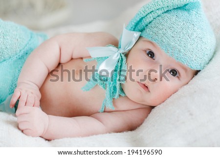 newborn baby girl in pink knitted bear hat on a bed