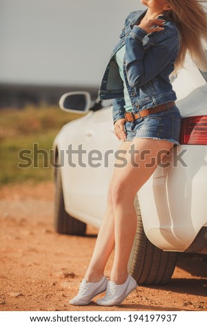 Beautiful young sexy woman near car outdoor. Rich hot blond slim girl with long healthy hair posing with luxury expensive automobile. Fashion model spring-summer