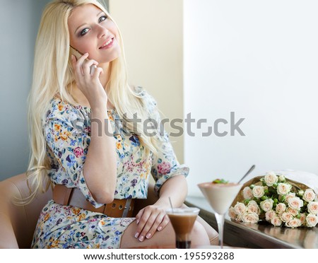 portrait of happy young blonde woman talking on the cell phone in a cafe. Smiling beautiful woman