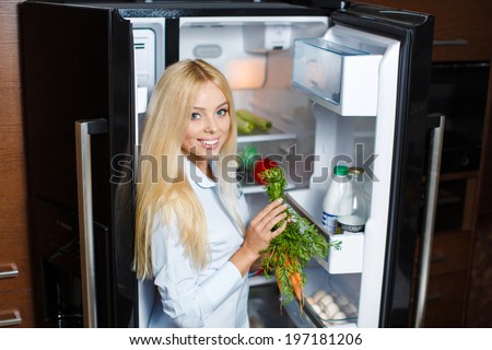Healthy Eating Concept. Diet. Beautiful Young Woman near the Fridge with healthy food. Fruits and Vegetables in the Refrigerator. Vegan food