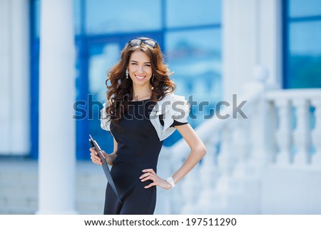 Business woman standing in foreground with a tablet in her hands, her co-workers discussing business matters in the background, tilt up