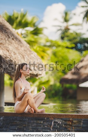 Spa vacation retreat woman relaxing at luxury travel resort. Happy blissful asian young woman in bikini in meditation enjoying summer sun and tanning during holidays on Hawaii.