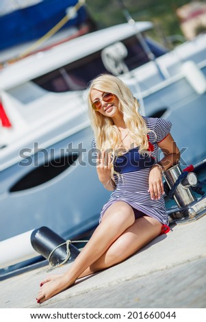 Adorable woman wearing sea Captain\'s cap and sexy sailor T-shirt. Attractive woman on a yacht on summer day