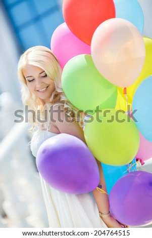 Happy beautiful bride with colorful latex balloons, outdoors. Happy young woman with big colorful latex balloons. Outdoors, lifestyle.