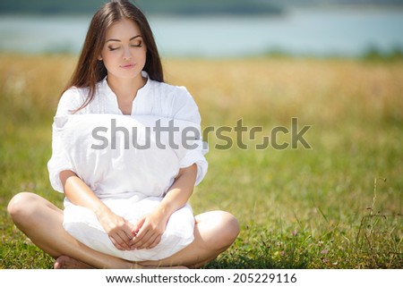 Young cute girl resting on soft pillow in fresh spring grass. Young woman sleeping on soft pillow in fresh spring grass.