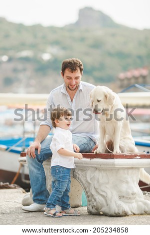 Father And Son Sitting With Dog On Straw Bales near sea. Happy father and little son with a big dog sitting over white background