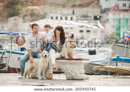Happy family resting at beach in summer. Happy family with dogs on berth in summer near the sea and yachts.