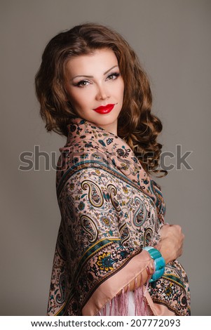 beautiful oriental look young woman with scarf on green background. portrait of a beautiful young woman with a scarf on her shoulders. Russian beauty. Russian national traditional scarf. Studio shot