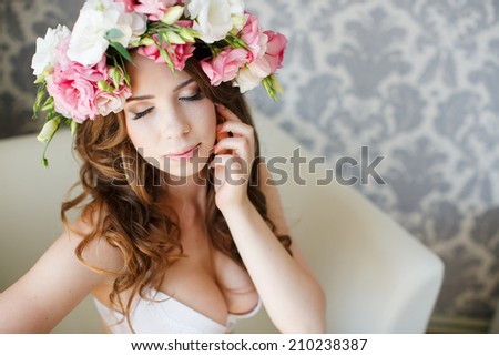beauty woman portrait with wreath of flowers sitting in armchair in light bedroom