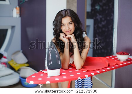 Happy young beautiful woman ironing clothes. Housework. Young beautiful woman ironing clothes in room. woman with iron, looking at camera and smiling
