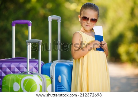 happy baby girl is going on a trip, pack a suitcase. happy little girl playing with a little retro suitcases outdoor. Child with airline tickets