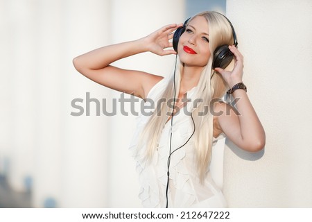 beautiful girl with long hair enjoys music with headphones in the sky with your eyes closed. Beautiful young woman with headphones. Enjoy music outdoors.