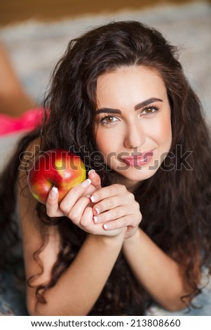 Portrait of lovely young woman holding a fresh ripe apple and smiling. Apple woman. Very beautiful ethnic model eating red apple