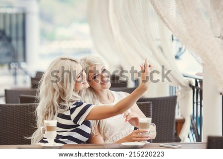 Two young women having coffee break together. Two women using a smart phone