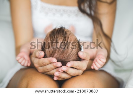 Mother holding head of her newborn son in hands. The baby on hands at mum. Loving mother hand holding cute sleeping newborn baby child