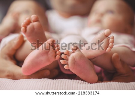 Baby feet in mother hands. Tiny Newborn Baby\'s feet on female Heart Shaped hands closeup. Mom and her Child. Happy Family concept. Beautiful conceptual image of Maternity. twins feet