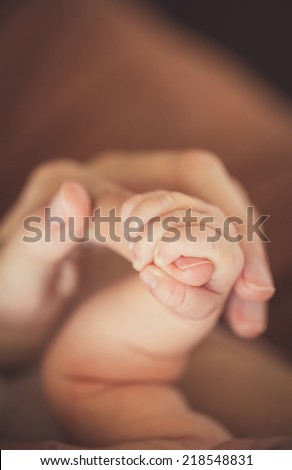 hand the sleeping baby in the hand of mother close-up. Extreme closeup of a baby\'s hand in mother\'s finger. Close-up of baby\'s hand holding mother\'s finger