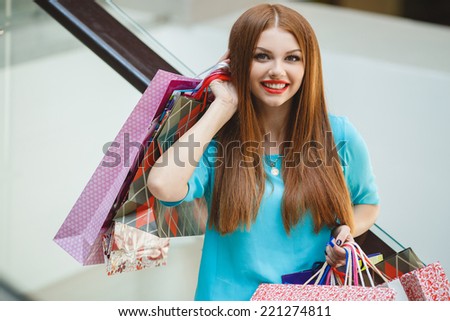 Happy woman shopping and holding bags at the mall. Shopping woman at the mall holding bags. Excited shopping woman holding bags with arms up