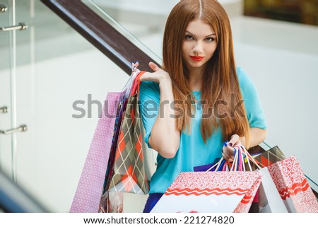 Happy woman shopping and holding bags at the mall. Shopping woman at the mall holding bags. Excited shopping woman holding bags with arms up