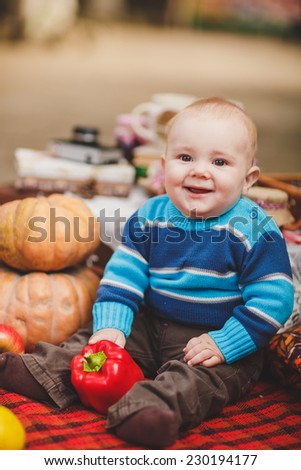 Happy child on autumn orange leaves, pumpkins.Outdoor. Infant in autumn garden. Autumn decorations