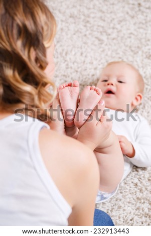 Newborn baby feet in mother\'s hands. Masseur massaging little baby\'s feet, shallow focus. studio portrait. Mother massaging her child\'s foot, shallow focus
