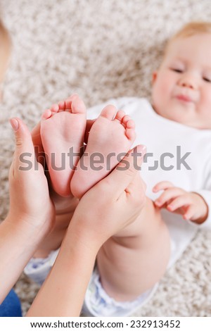 Newborn baby feet in mother\'s hands. Masseur massaging little baby\'s feet, shallow focus. studio portrait. Mother massaging her child\'s foot, shallow focus