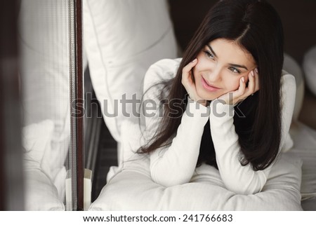 Woman lying in bed smiling. lady laying in bedroom at early morning. Woman lying in bedroom smiling near window.