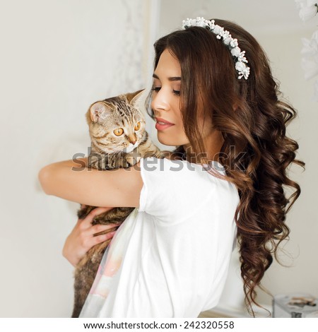 A gorgeous young woman with a cat on hands. close-up portrait of a beautiful girl holding british cat. Portrait of a beautiful girl at home