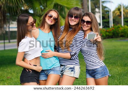 Group Of Four Teenage Girls Taking Picture In summer Park taking selfie photo using smartphone