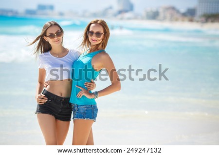 Two beautiful girls at beach. Young girls on vacation by the sea. Two girls sitting on the ocean coast. Group of woman at the sea