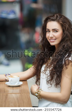 Woman drinking coffee at cafe. Portrait of young beautiful woman sitting in a cafe indoor drinking coffee. Young woman drinking coffee in a trendy cafe