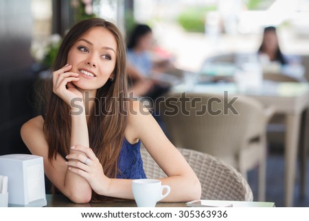 pretty young woman sitting in the cafe with a cup of tea or coffee. Charming woman in a restaurant.