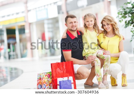 Mother, daughter and father in shopping mall. Family with shopping bags having fun smiling. Man, woman and child go on shopping.