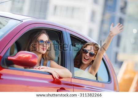 two girls friends in car. summer vacation. Friends going on road trip travel on summer day. freedom. cheering joyful with arms raised